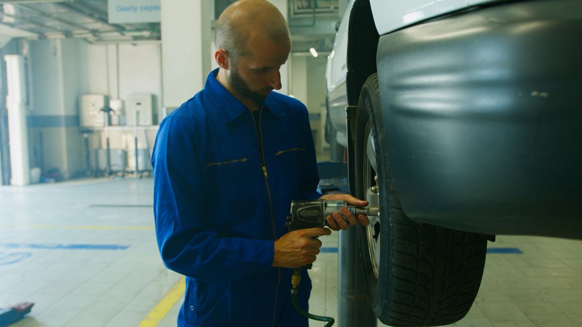 Technician servicing a vehicle tire with an impact wrench