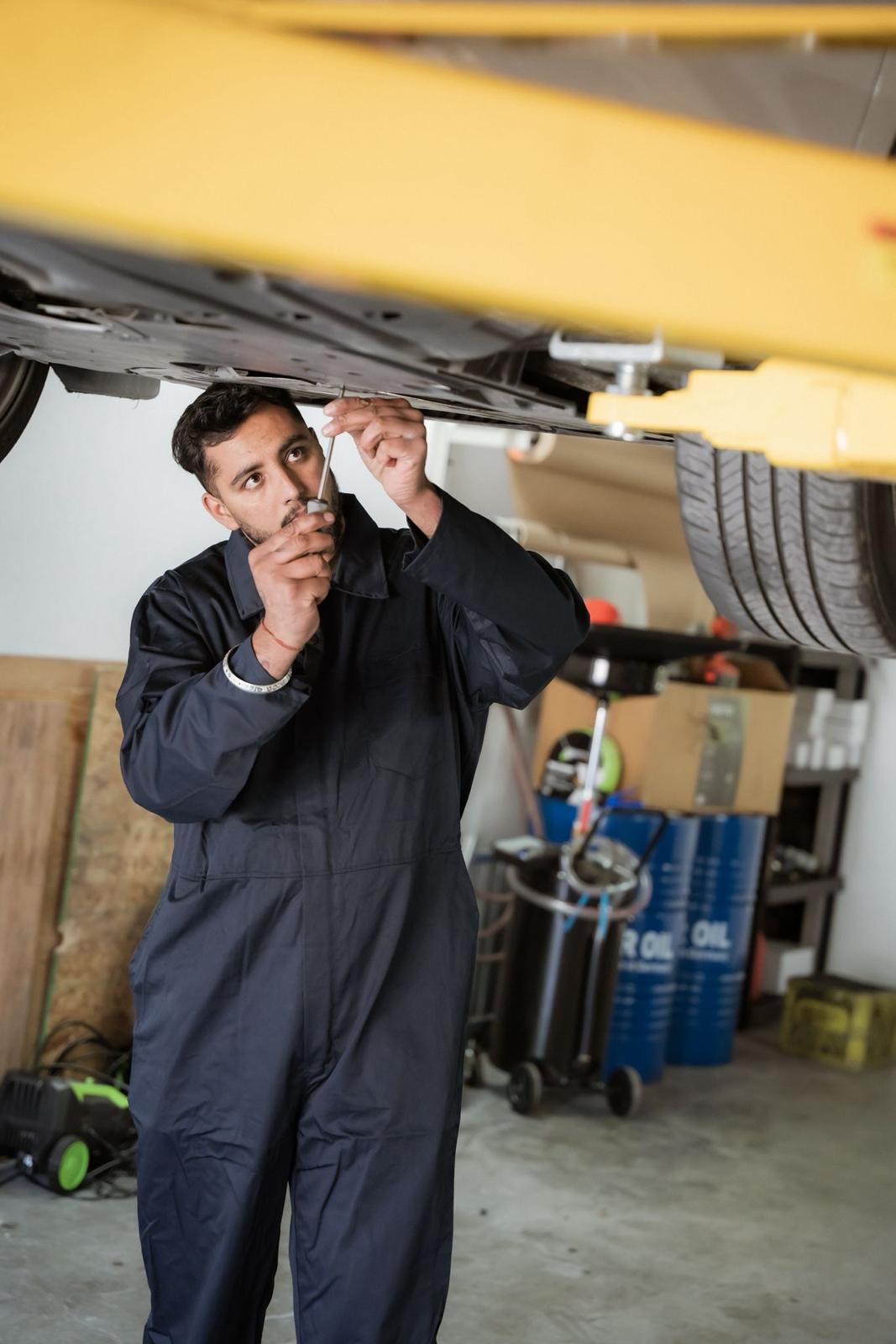 Mechanic inspecting the underside of a vehicle on a lift